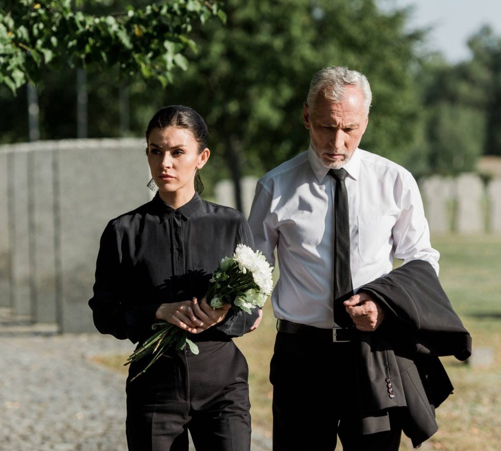 handsome-senior-man-standing-with-attractive-woman-holding-flowers-on-funeral.jpg